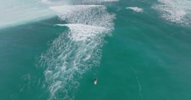 Sörf tahtasındaki kişi. Sörf tahtasında kürek çeken insanların hava görüntüsü. Okyanustaki insanın yukarıdan görünüşü. Yaz sporları