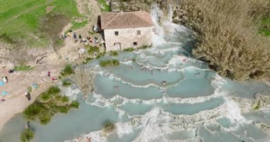 Saturnia, İtalya, Şubat 2022: Saturnia Termal Hamamları. Güzel termal şelalelerin hava manzarası. Doğada sıcak suda dinleniyor.