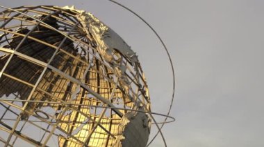 Günbatımında Queens NYC 'de Unisphere Globe, Dünya Küresi' nin arkasında görünen uçak. New York 'taki Flushing Meadows Corona Parkı' nda güzel bir günbatımında