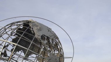 Unisphere Globe 'un arkasında uçak beliriyor. Uçan uçak ve devasa Dünya Küresi