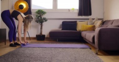Genç bir kadın spor yaptıktan sonra spor salonunu paspaslıyor. Evde egzersiz ve yoga seansının başarıyla tamamlanması