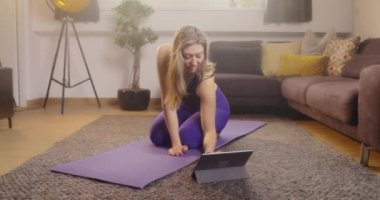 Kadın evde spor ve spor dersi için tablet kontrol ediyor. Çevrimiçi antreman sınıfına katılan genç bir kadın