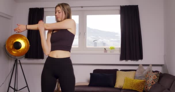 ホームワークアウトの前にストレッチ女性 上の体を伸ばしながら居間に立つ若い女性 — ストック動画