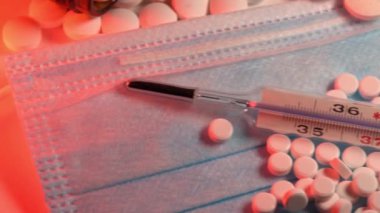 Üstünde haplar ve termometre olan klinik maske. İlaç ve klinik termometre