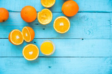 Bir bardak doğal portakal suyu, bazıları bütün, bazıları sıkılmış, diyet için, mavi ahşap bir masada. Sağlıklı kahvaltı.