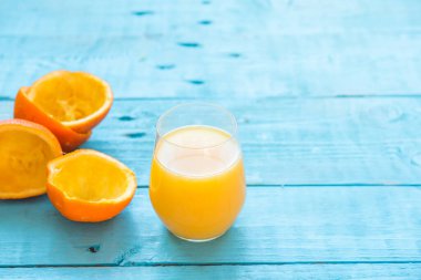 Bir bardak doğal portakal suyu, bazıları bütün, bazıları sıkılmış, diyet için, mavi ahşap bir masada. Sağlıklı kahvaltı.