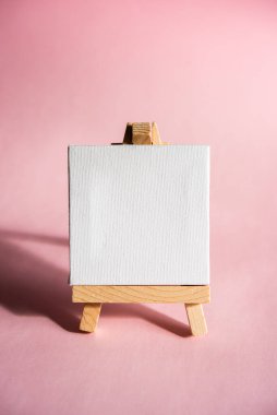 Kürsü, beyaz tuvalli sehpa ve pembe arkaplanda mesaj için yer