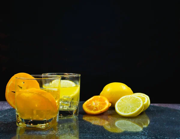 fresh orange and lemon in juice glass, near slice orange and lemon on table, bartender prepare fruit cocktail or fresh juice for drinking in party at bar