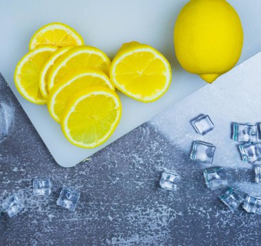 Limon ve taze limon dilimlerinin üst görüntüsü masada buzun yanında, barmen meyve kokteyli ya da barda içmek için taze meyve suyu hazırlar.