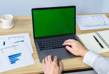 Çalışma masasında dizüstü bilgisayar ve grafikle çalışmak, toplantı sunumu için yeşil ekran, iş dünyası veri grafiği üzerinde çalışan profesyonel iş adamı