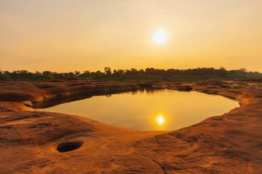 Dağdaki küçük göldeki su güneşin altın ışığını yansıtır gökyüzünden, gün doğumundan ya da batımından doğaya bakan manzara güneşin güzel altın güneş ışığını gösterir.