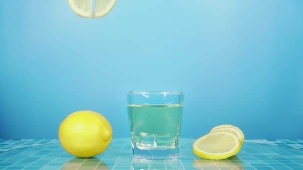 青いタイルのグリッドテーブルと青の背景にレモネードグラスにスライス新鮮なレモンを置きます バーテンダーはバーでパーティーで飲むためのフルーツカクテルや新鮮なジュースを準備します — ストック動画