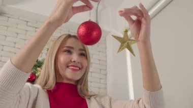 Kadınlar Noel ağacının yıldız ve top süslemeleriyle oynarlar. Romantik aşıkların yaşam tarzı. Yılbaşından önce ağaçla mutlu noeller.