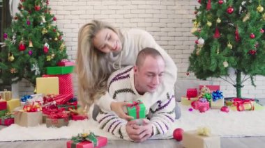 Çiftler Noel günü hediye kutusuyla öpüşürler. Romantik aşıkların yaşam tarzı. Yılbaşından önce Noel ağacıyla mutlu Noeller.