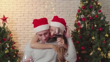Çiftler Noel günü şarap içerken birbirlerine sarılırlar. Romantik aşıkların yaşam tarzı. Yılbaşından önce Noel ağacıyla mutlu Noeller.