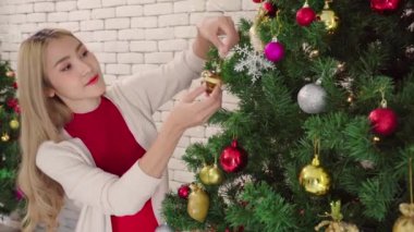 Kadınlar güler ve Noel ağacında çan süsü süsler, çift aşığının yaşam tarzı mutlu noel tatilleri evde yılbaşından önce ağaçla