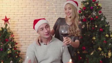 Mutlu, neşeli bir çift şarap ve Noel günü kameraya bakın. Romantik çiftlerin yaşam tarzı. Mutlu noeller, Noel tatilleri.