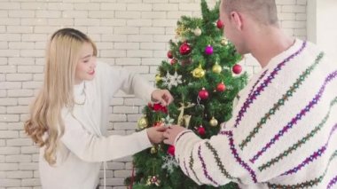 Mutlu çift Noel 'de ağaçtaki kar süslerini süslerler. Romantik çiftlerin yaşam tarzları. Mutlu noeller Noel tatilleri.