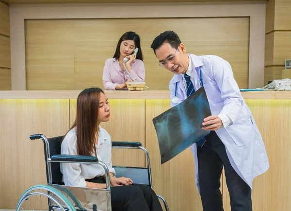 doctor explain xray result to patient sitting on wheelchair, doctor with stethoscope medical treat health of patient at hospital
