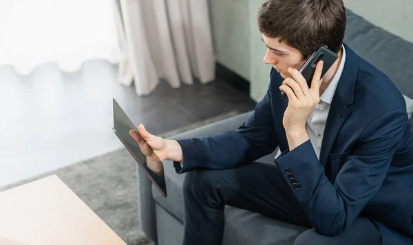 Kafkasyalı işadamı cep telefonundan arıyor, tabletle çalışıyor, takım elbise giyiyor, oturuyor, pencere arkasını aydınlatıyor. Genç adam ofis geçmişi ve fotokopi alanı olan bir işte çalışıyor.