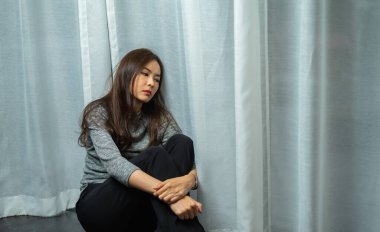 Üzgün oturan genç bir kadın, depresyonda olan bir kadın, karanlık odada güneşlenmeye bakan bir kadın, güzel bir kadın ya da bir kızın portresi depresyonda olan yalnız başına oturan bir kız.