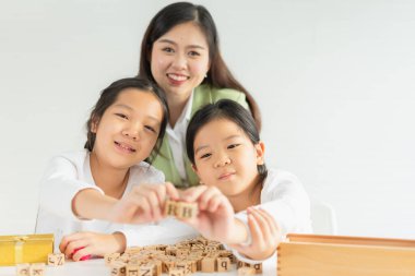 Bir grup çocuk ve öğretmen mutlu, gülümse, eğlen, alfabeyi göster, küçük çocuğa odaklan. Asyalı çocuklar küçük okullarda alfabe, scrabble, çapraz bulmaca çalışıp öğrenirler.