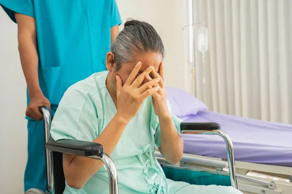 Elder patient sick brain and eye disease sitting on wheelchair with suffering, sadness. Doctor or nurse take care senior patient health admission at hospital