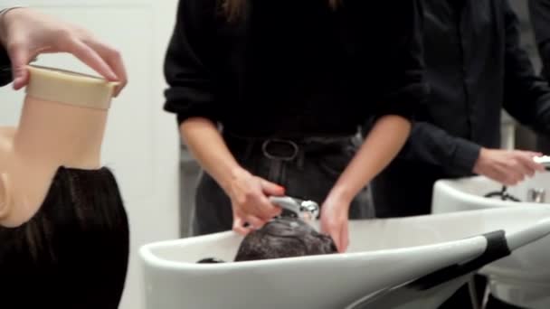 Студенты моют волосы манекенов на курсах парикмахеров — стоковое видео