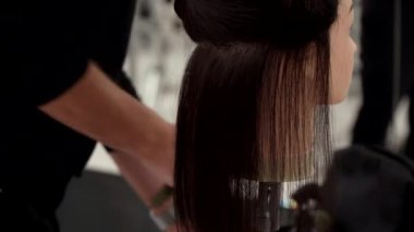 Siyah elbiseli beyaz adam mankenlerin saçlarını kesiyor.