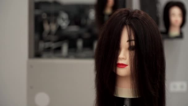 Кавказький хлопець у чорному одязі підстригає волосся манекенів. — стокове відео