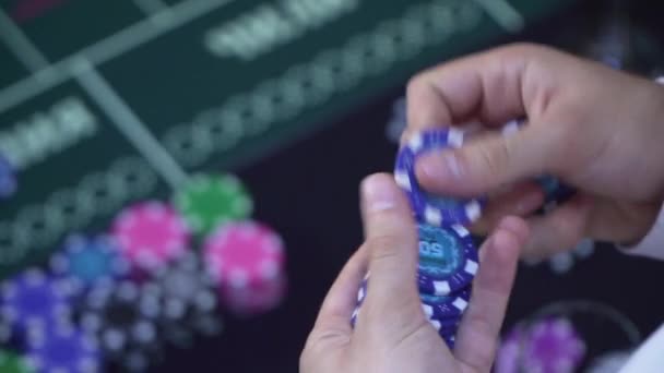 Мужчина в белой рубашке держит в руках фишки для покера — стоковое видео