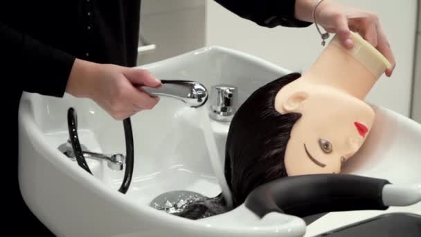 En flicka i svarta kläder tvättar håret på en skyltdocka på en frisör kurs — Stockvideo