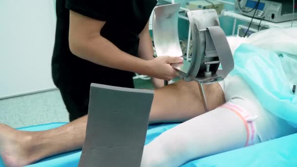 O cirurgião coloca a perna do paciente em um suporte — Vídeo de Stock