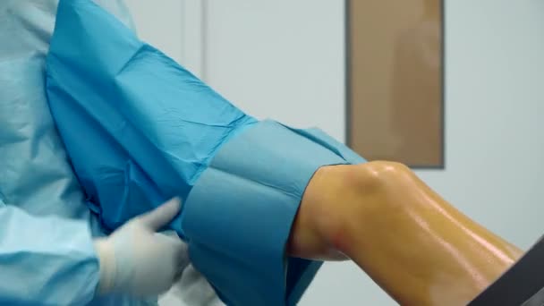 Der Chirurg befestigt das schützende Gewebe am Bein des Patienten — Stockvideo