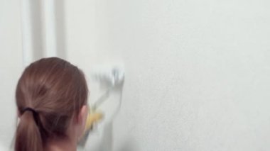 Beyaz kız duvarları silindirle boyuyor. 
