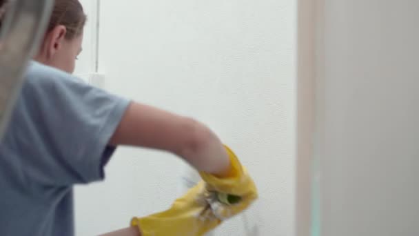 Caucasian girl paints the walls with a roller — Stock Video