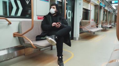 Tıbbi maskeli bir adam telefona bakar. Boş bir metro vagonuna.