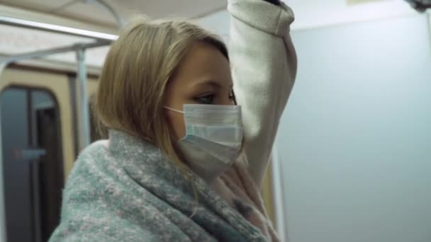 Menina em uma máscara médica olha para a câmera no transporte — Vídeo de Stock