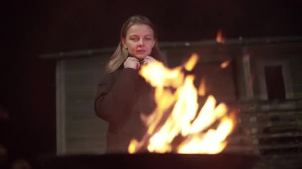 Una chica caucásica se calienta cerca del fuego — Vídeos de Stock
