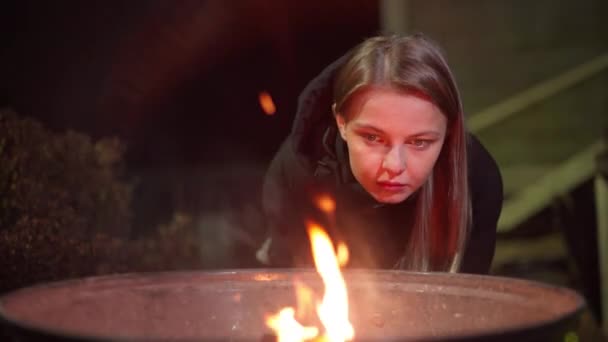 Кавказька дівчинка зігрівається біля вогню. — стокове відео