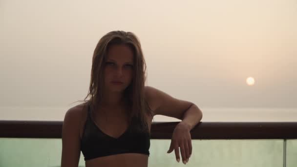 Girl looking at the camera on the background of the sunset. — Video Stock