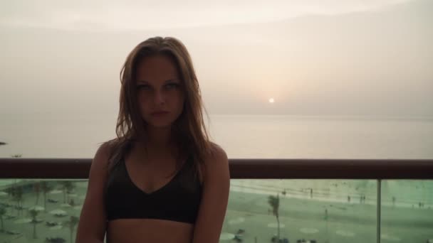 Chica mirando a la cámara en el fondo de la puesta de sol. — Vídeo de stock