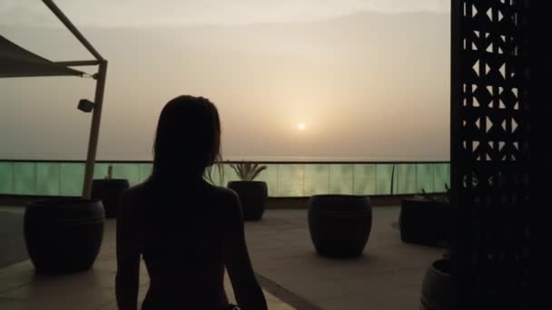 細い美しい白人の女の子が夕日の背景を歩いています — ストック動画