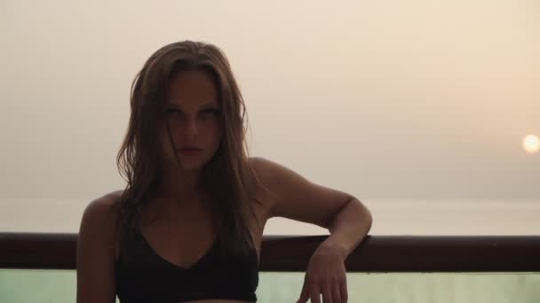 Girl looking at the camera on the background of the sunset. — Video