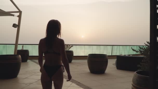 A slender beautiful Caucasian girl is walking on a sunset background — Video