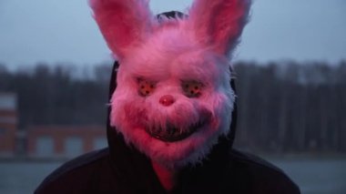 scary evil maniac in a rabbit mask looks at the camera and prepares to kill