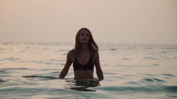 Girl bathes in the sea against the backdrop of the sunset — Stockvideo