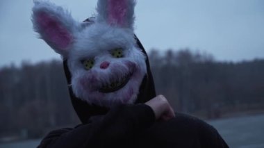 scary evil maniac in a rabbit mask looks at the camera and prepares to kill