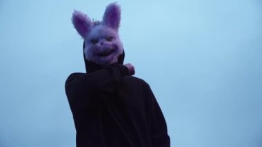 scary evil maniac in a rabbit mask looks at the camera and prepares to kill