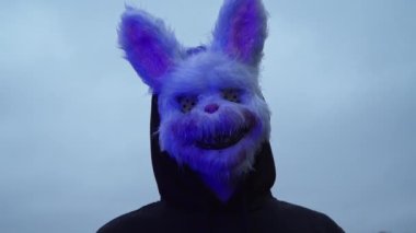 scary evil maniac in a rabbit mask looks at the camera and prepares to kill